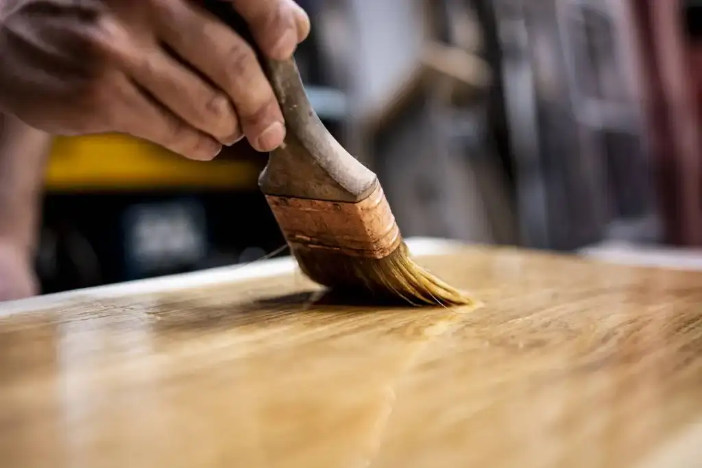 pinceau étalant de l'huile naturelle pour le meuble en bois massif