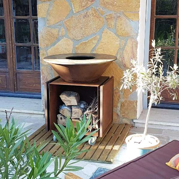 brasero artisanal en acier effet rouille pour barbecue avec rangement pour buche de bois et plan de travail pliable